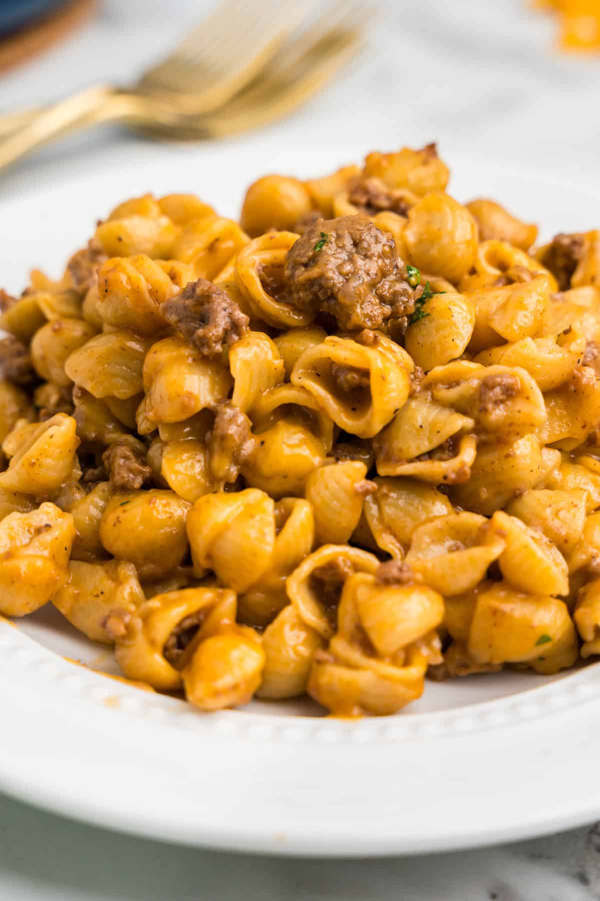 Detailed macro view of cooked cheesy pasta shells with ground beef inside the pot.

