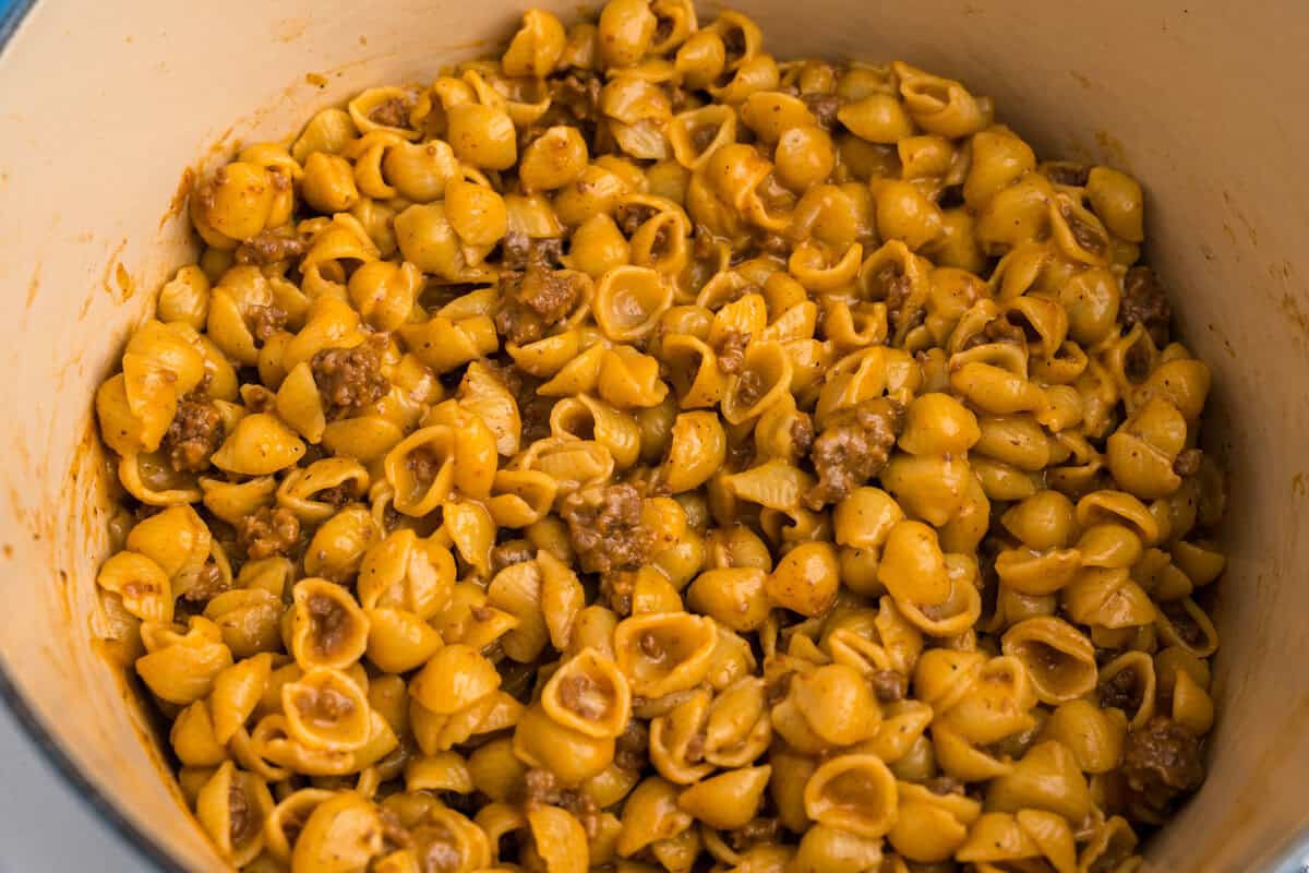 A serving of cheeseburger pasta plated on a white dish with golden forks in the background.