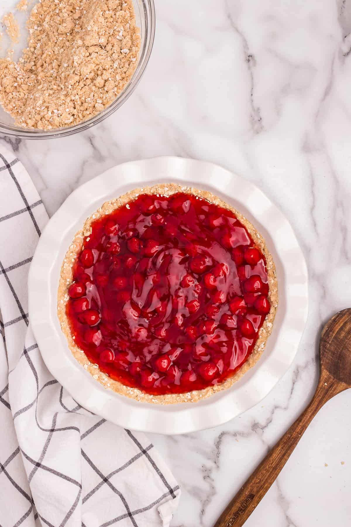 Cherry pie filling spooned onto the crust, glossy and vibrant red.