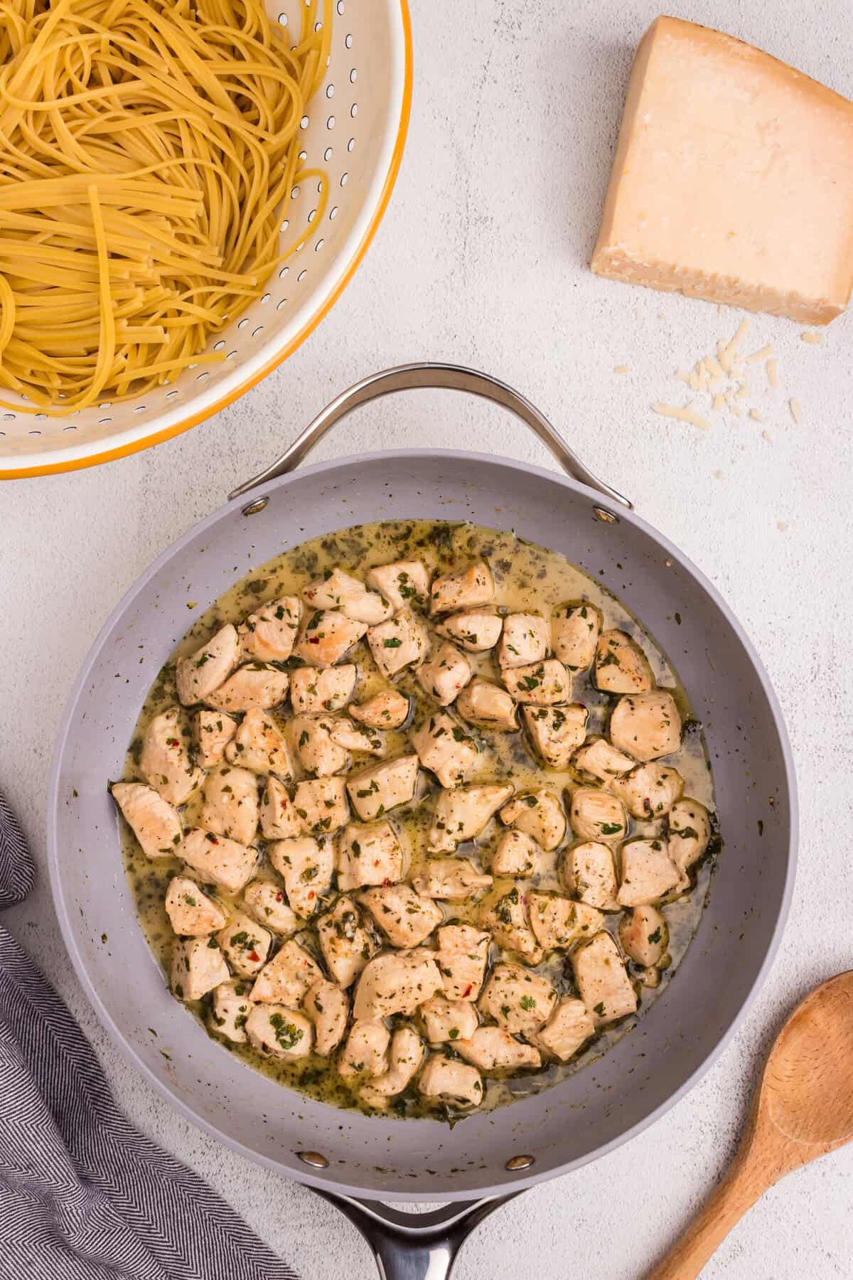 Chicken simmering in a skillet with melted butter, herbs, and garlic sauce, forming the base for chicken scampi