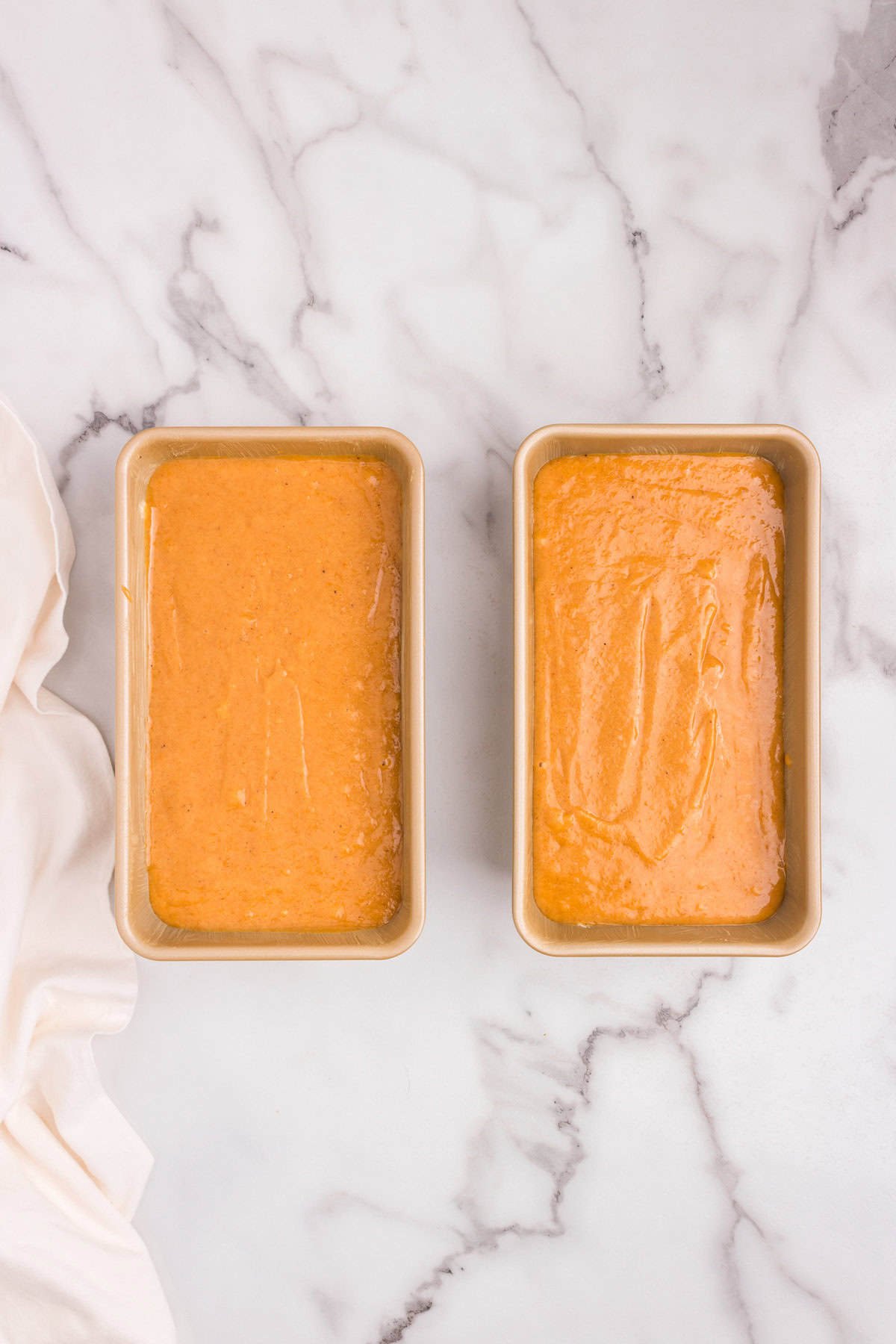 Loaf pans filled to the top with a final layer of pumpkin batter, ready to go into the oven.
