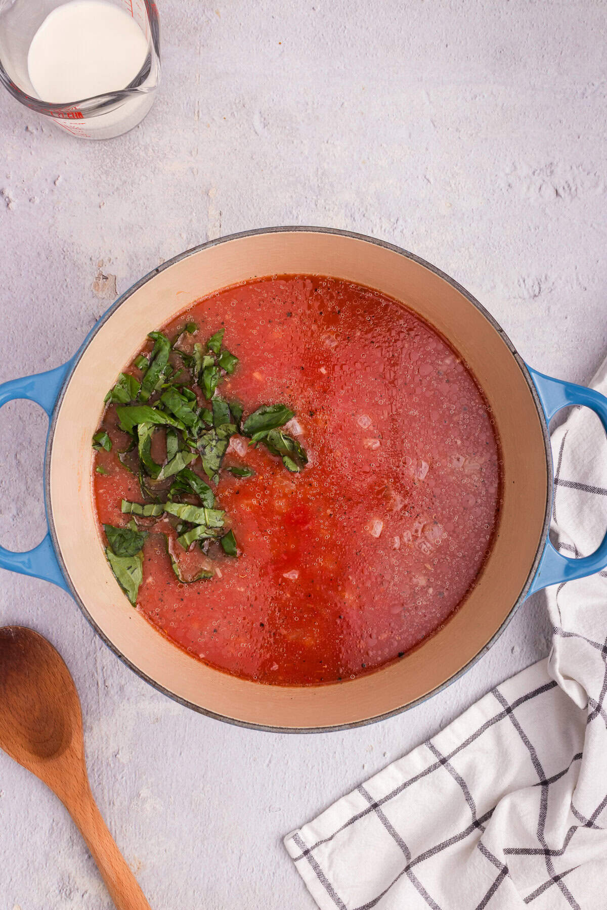 Crushed tomatoes and chopped fresh basil added to the pot with the cooked onions, creating a tomato soup base.
