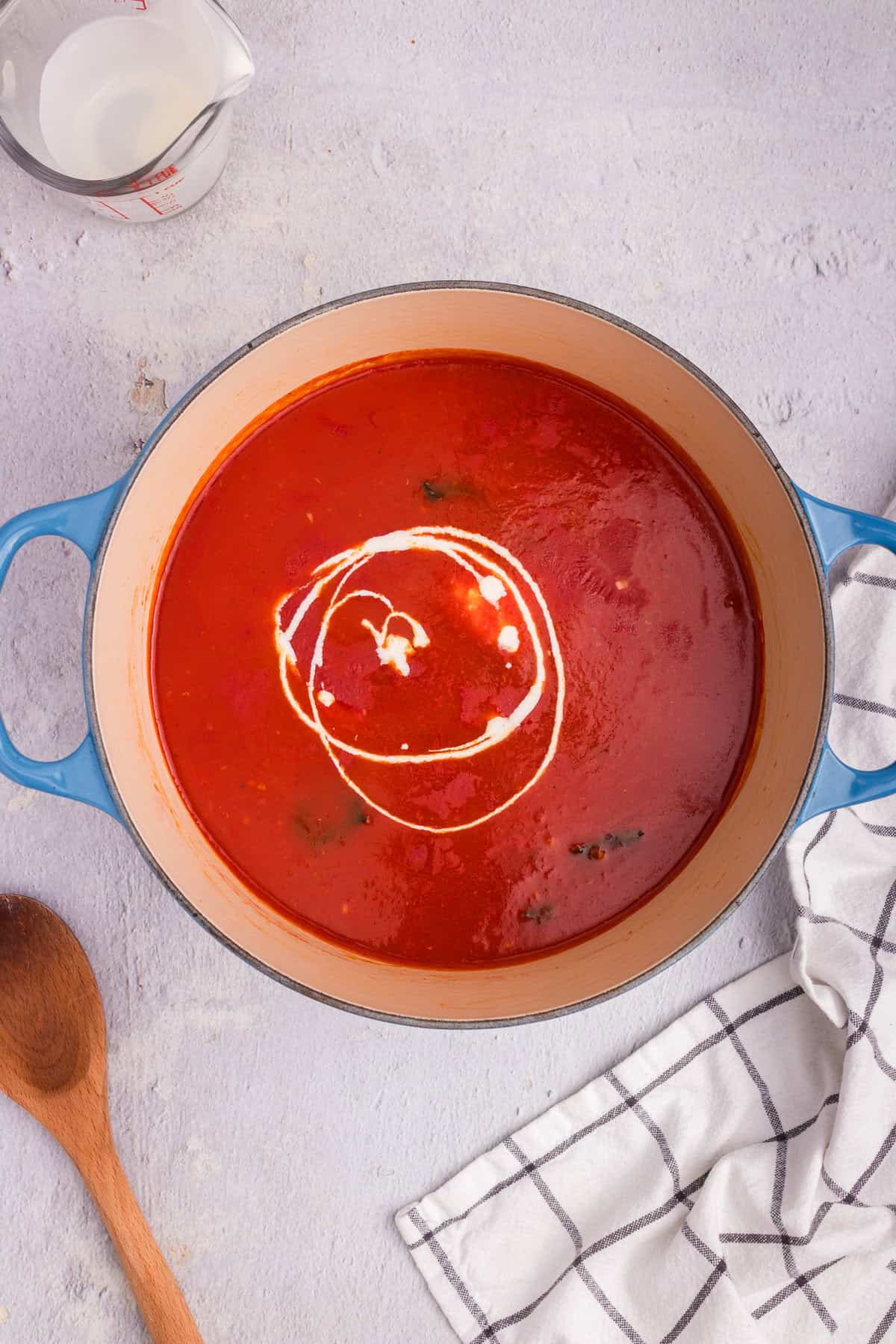 Cream being swirled into the tomato soup mixture, adding richness and creaminess.