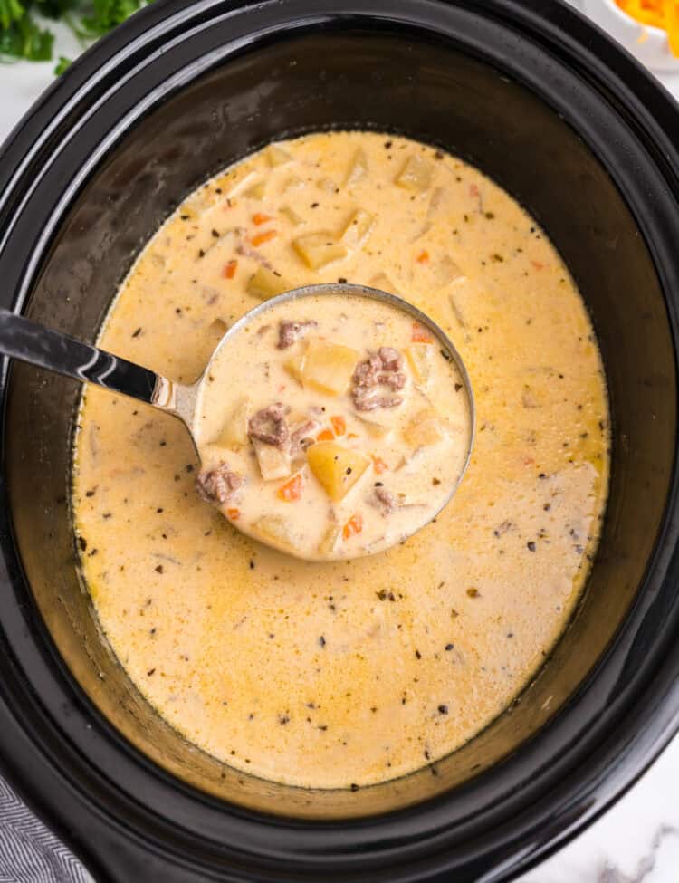 Ladle spooning Crock Pot Cheeseburger Soup out of crock pot