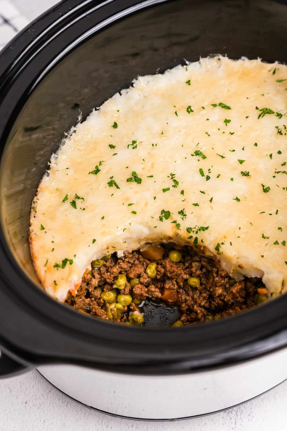 Close-up of a spoonful of shepherd’s pie showing ground beef, carrots, peas, and mashed potatoes.
