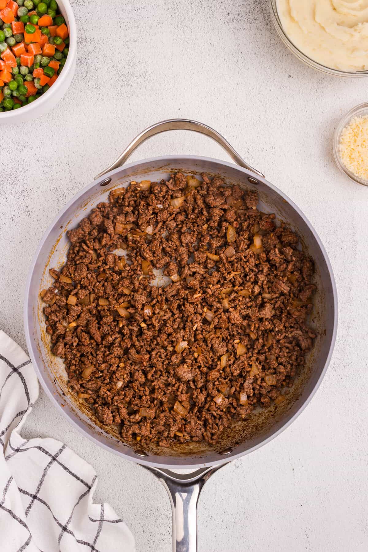 Cooked and seasoned ground beef mixture with softened onions and garlic fully combined in a skillet.