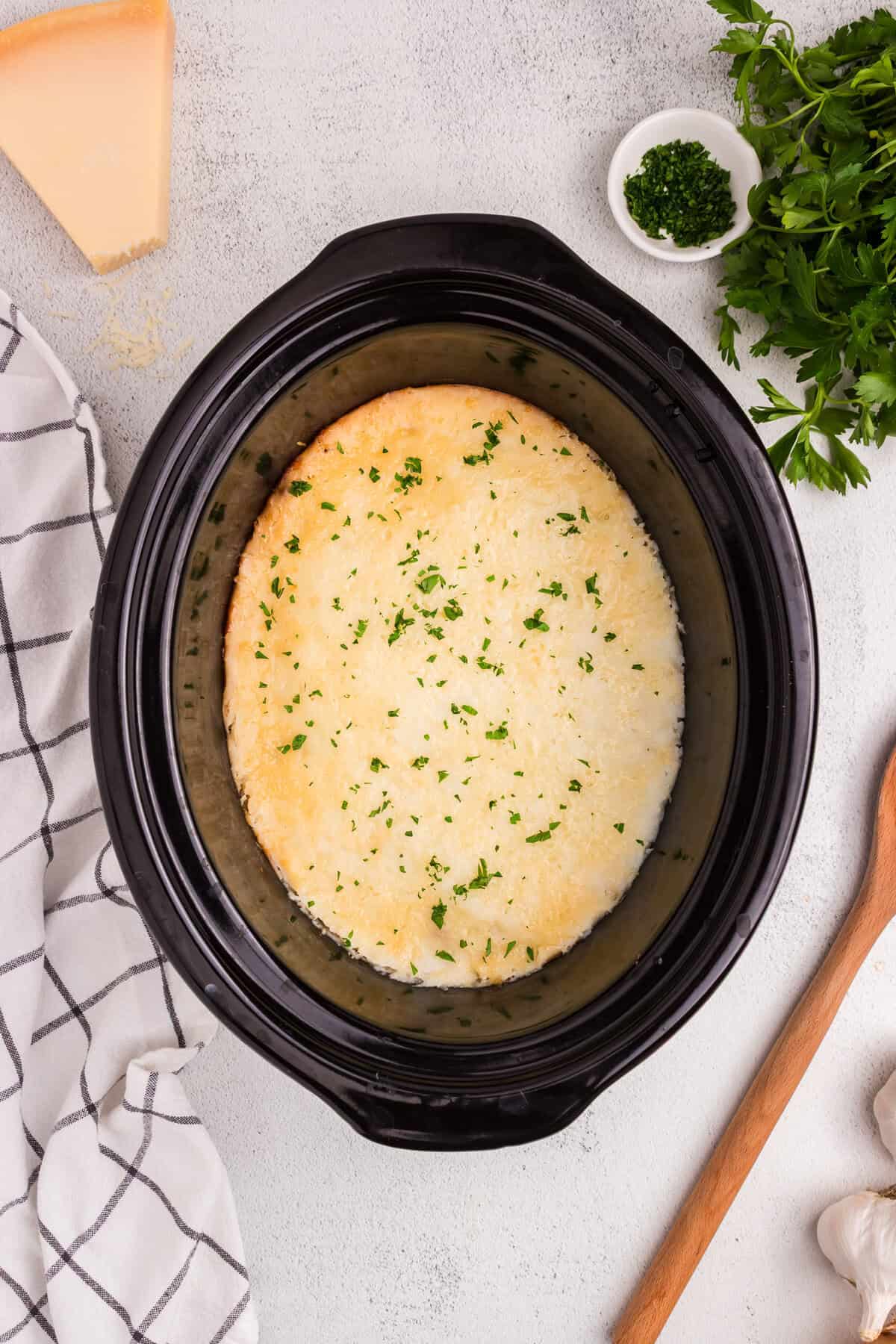 Fully cooked shepherd’s pie in slow cooker with golden mashed potato topping garnished with chopped parsley.