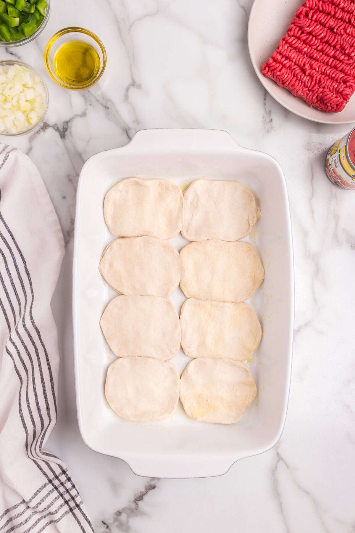 The same baking dish, but the biscuit dough rounds are now flattened, creating a single-layer crust at the bottom.