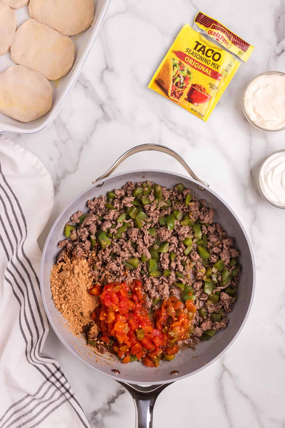 The same skillet, now with browned ground beef, softened bell peppers, taco seasoning, and diced tomatoes mixed in.