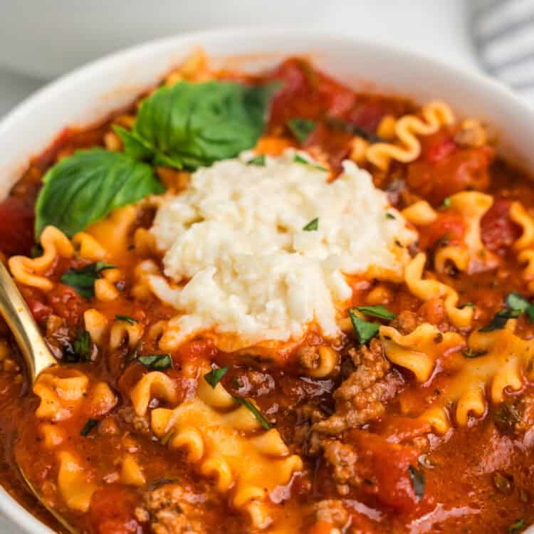 Close up image of completed Lasagna Soup in a white bowl with a spoon in it.