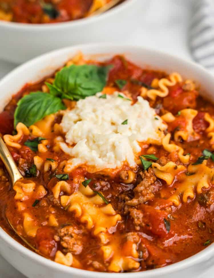 Close up image of completed Lasagna Soup in a white bowl with a spoon in it.