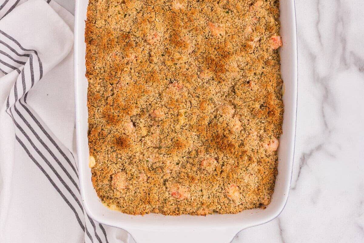 Baked lobster mac and cheese in a white casserole dish, fully topped with a golden brown breadcrumb crust.