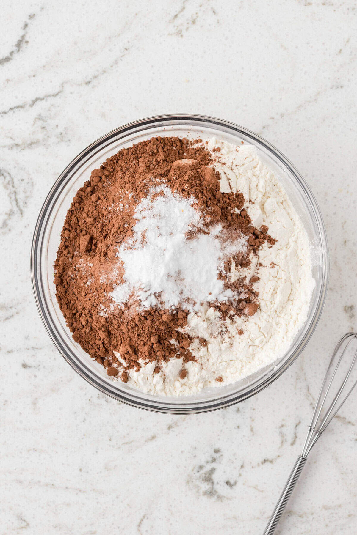 A bowl with dry ingredients: flour, cocoa powder, baking soda, and salt, not yet mixed.