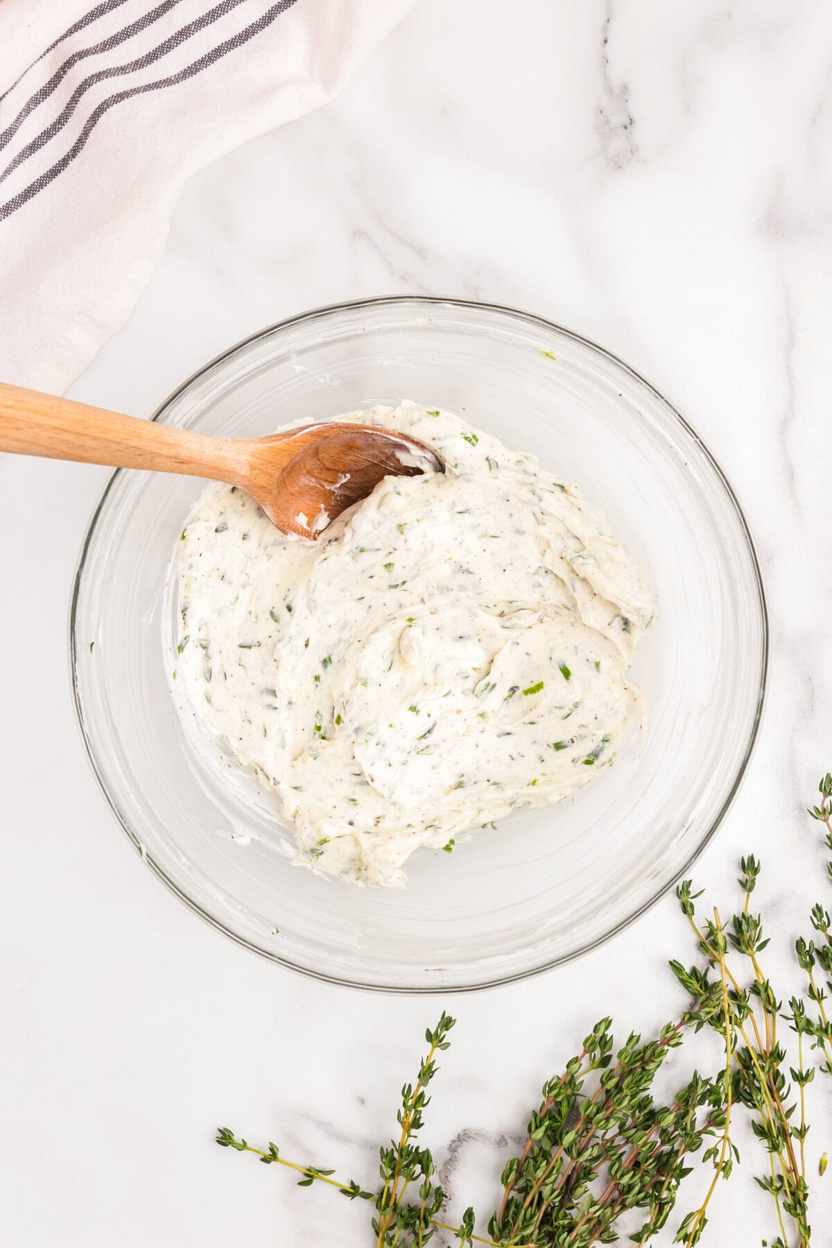 Overhead picture of herb butter ingredients combined with wooden spoon.