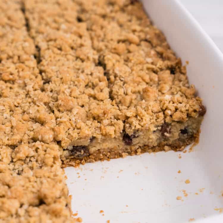 Side view of the pan with several bars removed, revealing the inside layers of the oat crust, creamy raisin filling, and crumble topping.
