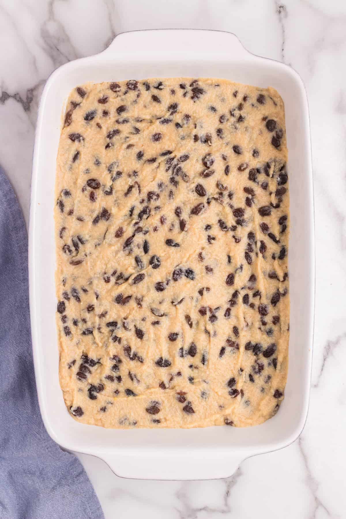 A baking dish filled with the sour cream and raisin filling spread evenly over the baked oat crust.