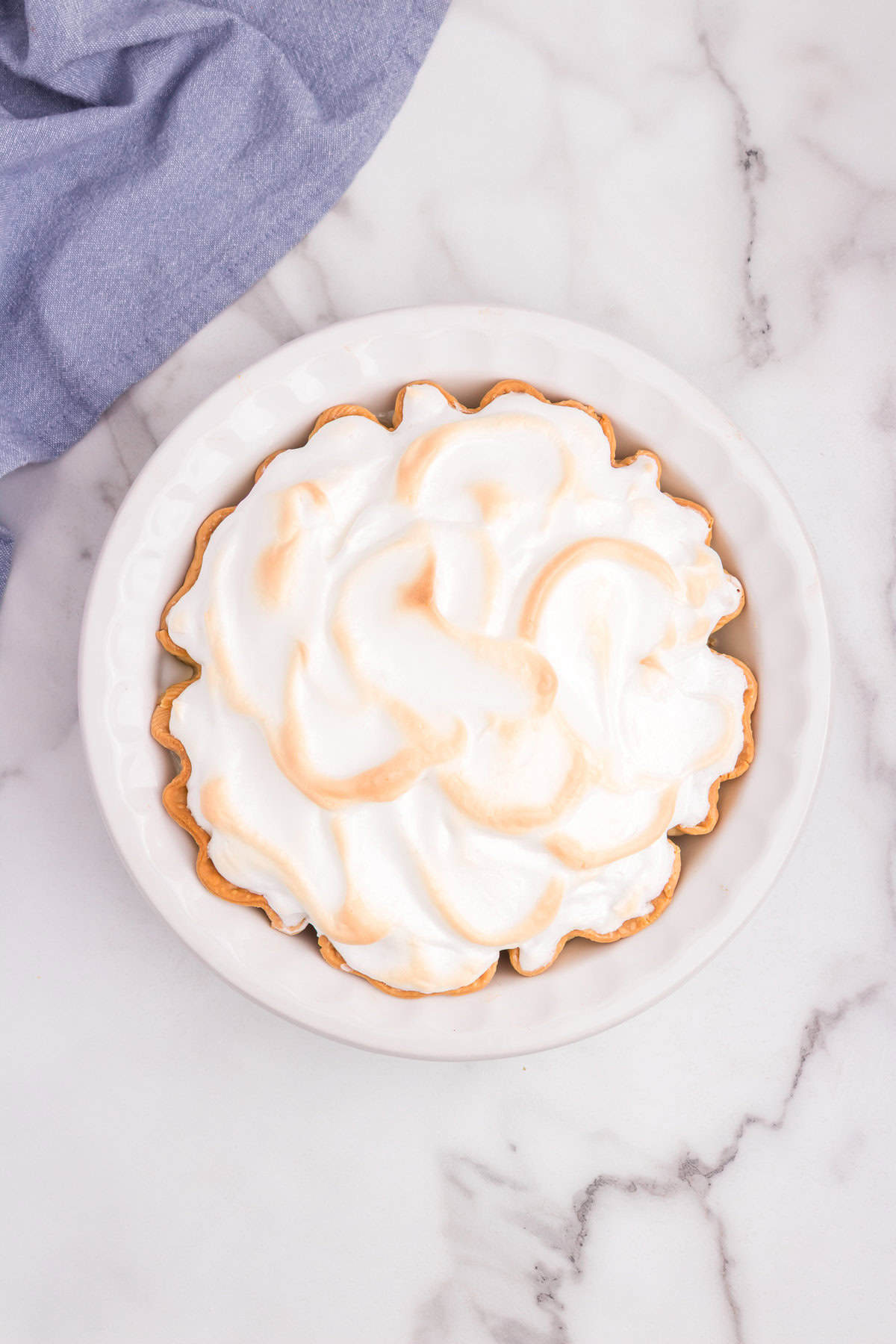 The baked pie shows golden brown swirls on the meringue topping, ready to serve.