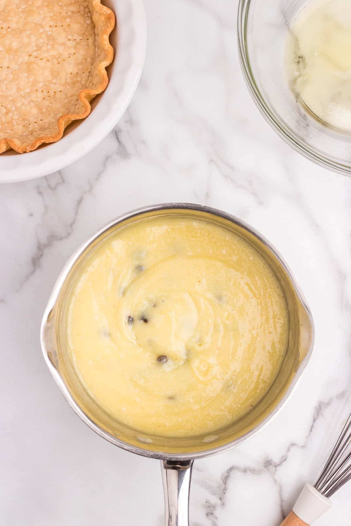 The saucepan now contains thickened yellow custard with raisins evenly mixed in.