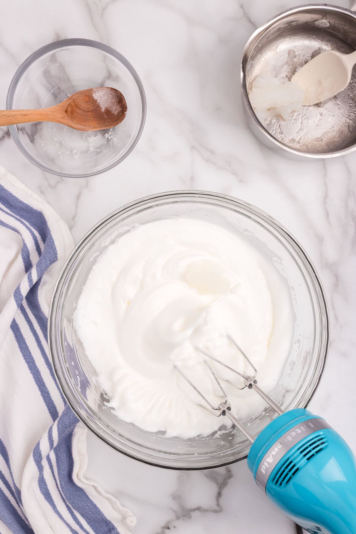 Egg whites beaten to stiff peaks with an electric mixer, ready to be combined with sugar and thickened cornstarch mixture.