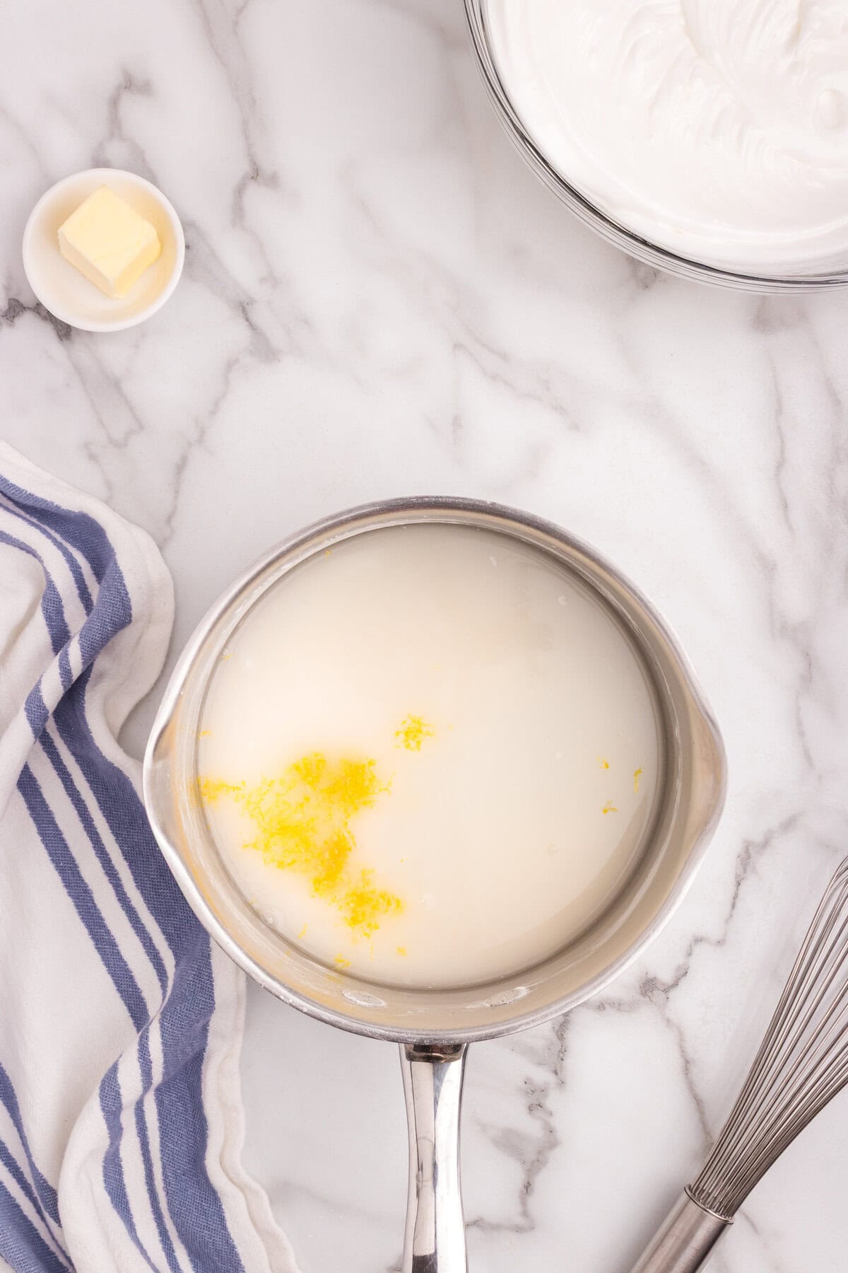 A saucepan with sugar, flour, water, and lemon zest before heating, with butter waiting to be added.