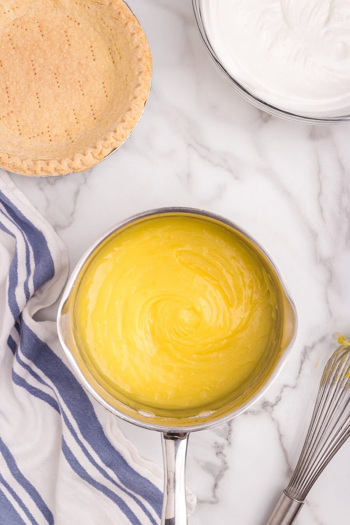 Smooth, glossy lemon custard filling in the saucepan, thick and fully cooked, ready for the pie crust.