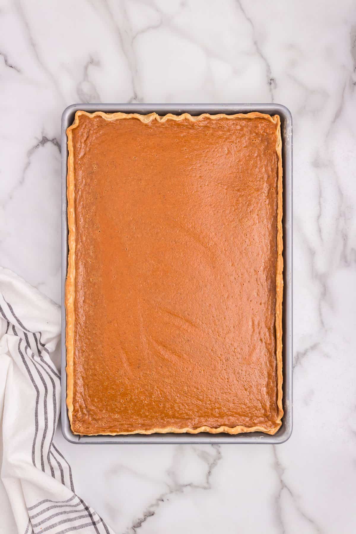 Baked sheet pan pumpkin pie, golden brown on top, cooling in the pan.